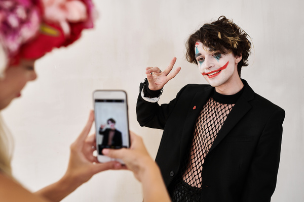 Woman with Wreath Takes Pictures of Smiling Man with Joker Makeup